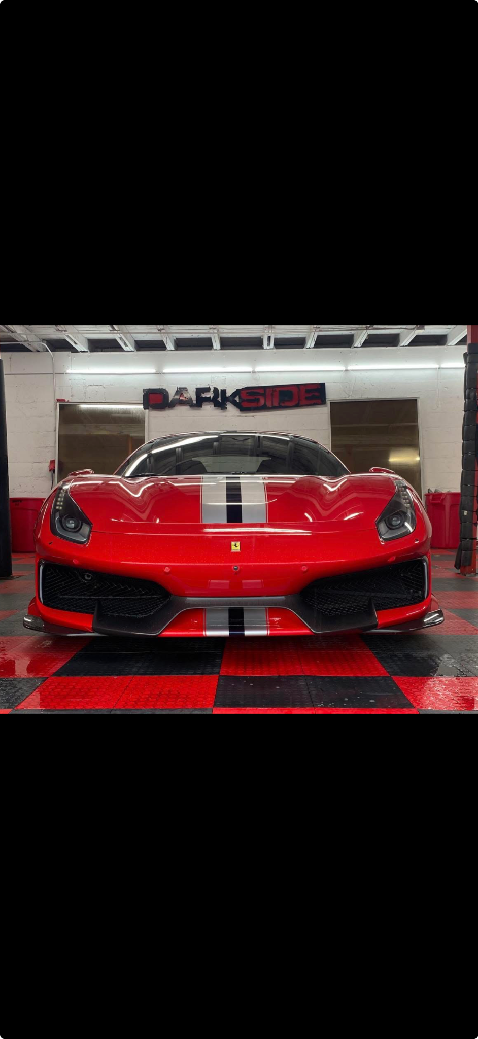 Red Ferrari with racing stripes inside the Darkside Window Tinting shop
